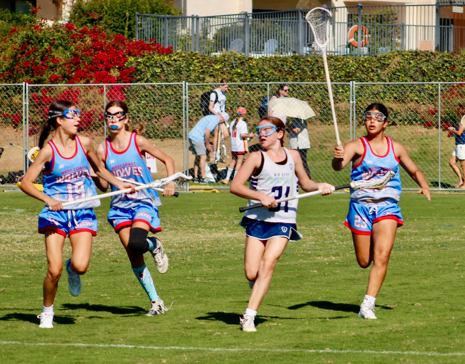 A Reign player carrying the ball between defenders during a lacrosse game